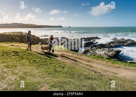 Persone che camminano il loro cane lungo il sentiero della costa sul promontorio di Newquay in Cornovaglia. Foto Stock