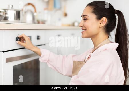 Donna che usa il cibo di cottura della stufa in cucina Foto Stock