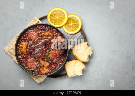 Feijoada in nero ciotola grigio tavolo. Cucina brasiliana e portoghese tradizionale fagioli stufato di carne Foto Stock