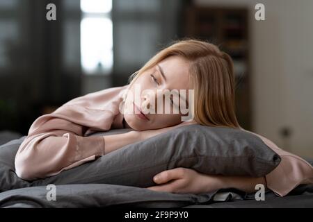 Giovane donna sdraiata sul cuscino con gli occhi chiusi e dormendo durante il suo tempo di relax Foto Stock