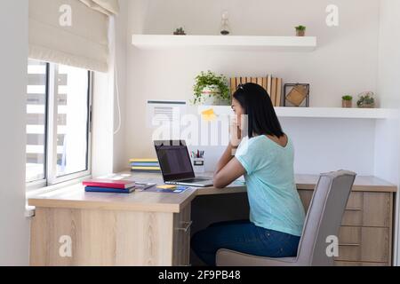 Razza mista genere fluido uomo che lavora a casa usando un laptop. Stare a casa in isolamento durante il blocco della quarantena. Foto Stock