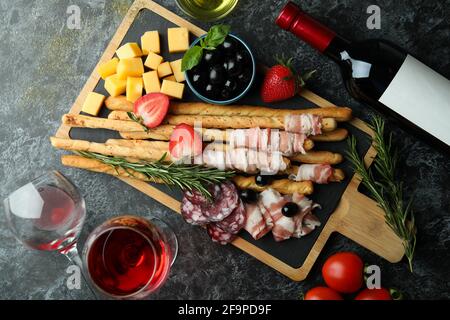 Sali a bordo con grissini e spuntini e vino su sfondo nero fumé Foto Stock