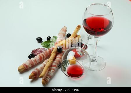 Grissini con pancetta, spuntini e vino su sfondo bianco Foto Stock