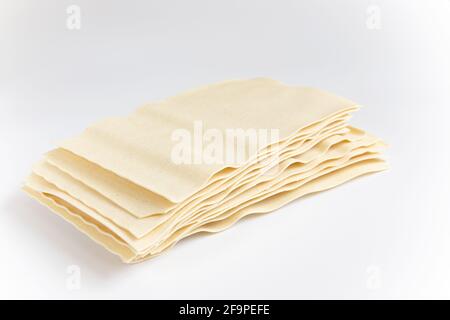 Pila di fogli di lasagna non cotti isolati su sfondo bianco Foto Stock