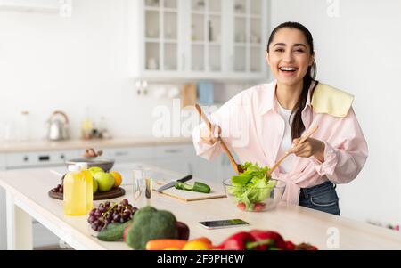 Ritratto di giovane donna sorridente che cucinava insalata fresca Foto Stock