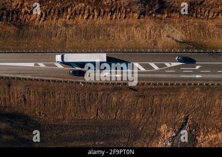 Semi-camion e due auto sulla strada attraverso la campagna, da sopra drone fotografia Foto Stock
