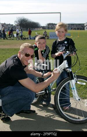 Girvan, Ayrshire, Scozia. REGNO UNITO. Il vincitore della medaglia Multi World e Olympic Chris Hoy, che aveva trascorso il pomeriggio divertendo il grande gruppo di giovani piloti iscritti alla gara inaugurale del circuito Scozzese dei giovani rinnovabili, disputata sullo stesso circuito. Foto di Chris Hoy che interagisce con i ciclisti Foto Stock