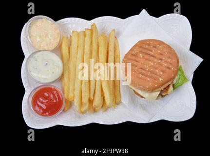 Vista dall'alto di patatine fritte con deliziosi burger sul vassoio e salse assortite su nero Foto Stock