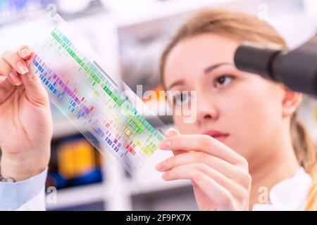 La giovane donna esamina un quadro di spettroscopia in una fisica quantistica laboratorio Foto Stock