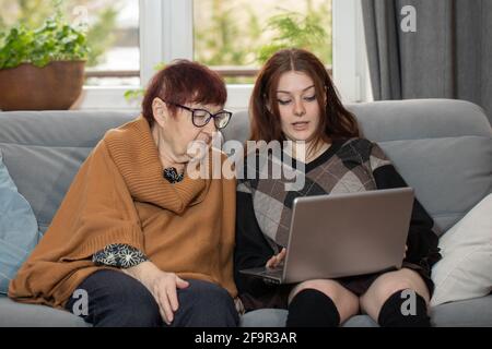 Giovane donna che insegna nonna a fare shopping online. Nonna e nipote che fanno acquisti online. Foto Stock