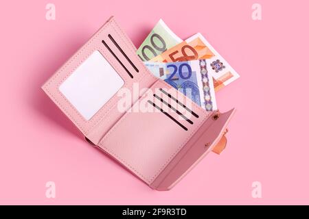 Borsetta rosa su sfondo rosa pastello con banconote in euro. Closeup di portafoglio in pelle aperta moderna e banconote europee. Finanza, investimenti, savin Foto Stock