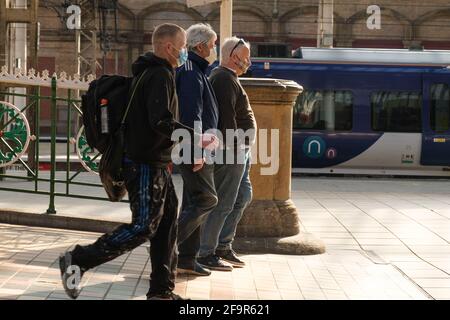 Tre uomini che indossano maschere che camminano sulle piattaforme alla stazione ferroviaria di Preston. Foto Stock