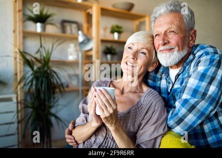 Felice coppia senior in amore abbracciando e legame con emozioni vere a casa Foto Stock