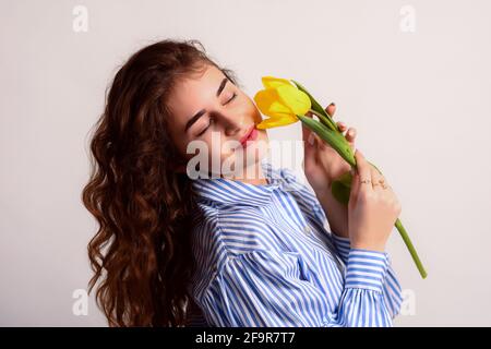 Una ragazza sognante con gli occhi chiusi tiene un fiore nelle sue mani. Foto Stock