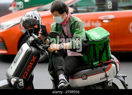 Bangkok, Thailandia. 20 Apr 2021. Un motociclista Grab controlla il suo telefono cellulare.durante la pandemia di Covid-19 la rete di servizio di consegna di cibo domestico di Grab si è espansa con migliaia di ex motociclisti in taxi a livello nazionale che si sono passati al servizio di consegna di Grab tramite l'app di Grab online. I clienti possono ordinare online i loro piatti thailandesi e occidentali preferiti da una varietà di ristoranti locali e popolari a Bangkok. (Foto di Paul Lakatos/SOPA Images/Sipa USA) Credit: Sipa USA/Alamy Live News Foto Stock