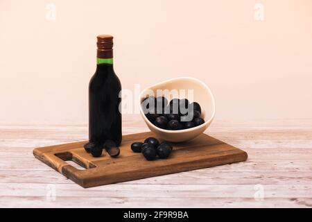 Piccola bottiglia di vino rosso Rivera de España su a. tavolo in legno con uve rosse su taglio in legno tavola e una ciotola di frutta fresca con selezione f Foto Stock