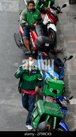 Bangkok, Thailandia. 20 Apr 2021. Un motociclista Grab controlla il suo telefono cellulare.durante la pandemia di Covid-19 la rete di servizio di consegna di cibo domestico di Grab si è espansa con migliaia di ex motociclisti in taxi a livello nazionale che si sono passati al servizio di consegna di Grab tramite l'app di Grab online. I clienti possono ordinare online i loro piatti thailandesi e occidentali preferiti da una varietà di ristoranti locali e popolari a Bangkok. Credit: SOPA Images Limited/Alamy Live News Foto Stock