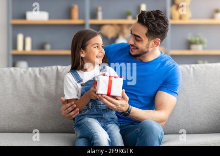 Ragazza amorevole che celebra il giorno del padre, salutando papà eccitato con presente Foto Stock