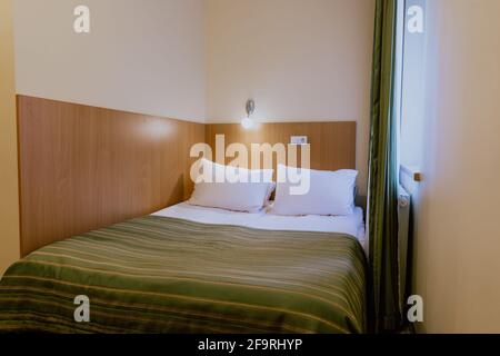 Letto matrimoniale in un hotel semplice e ben arredato camera durante il giorno Foto Stock
