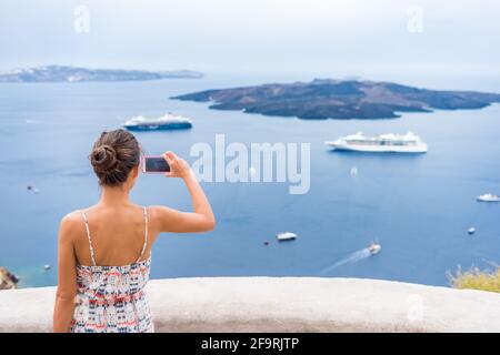 Europa crociera vacanza estate viaggio turista donna scattare foto con telefono del Mar Mediterraneo a Santorini, Oia, Grecia, con navi da crociera in barca a vela Foto Stock