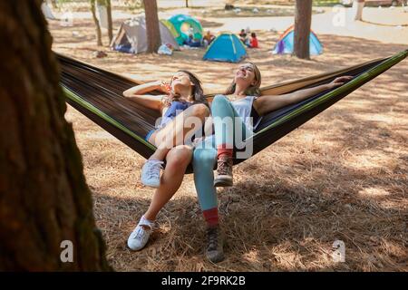 due amici che hanno un bel tempo nella loro amaca dopo al loro campeggio Foto Stock