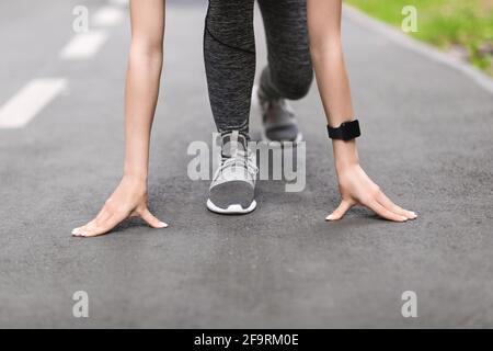 Pronti, partenza, via. Female Runner in piedi in posizione di partenza sul percorso all'aperto Foto Stock