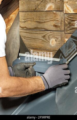 Un lavoratore sta installando e impermeabilizzando un camino sul tetto di una casa. Foto Stock