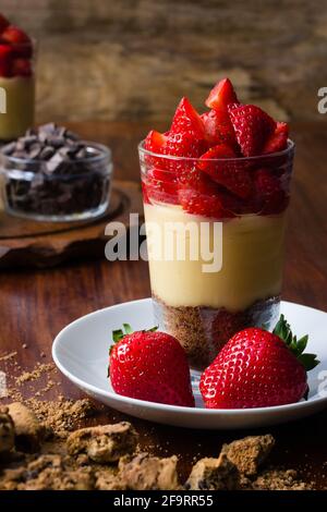 Dolce trifle di fragole dolce in vetro con budino e biscotti su sfondo di legno Foto Stock