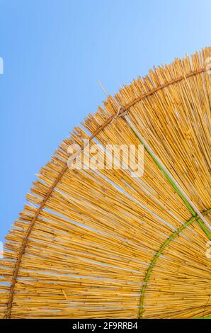 particolare di un parasolo di fieno con un cielo blu sullo sfondo. Foto Stock