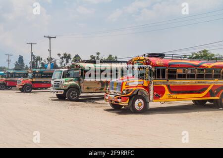ANTIGUA, GUATEMALA - 28 MARZO 2016: I colorati autobus di pollo, ex autobus scolastici statunitensi, sono allineati al terminal principale degli autobus nella città di Antigua Guatemala. Foto Stock