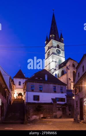 vista notturna sulla cattedrale luterana illuminata di santa maria in città rumena sibiu Foto Stock
