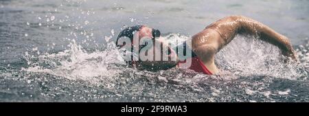 Nuoto triatleta uomo nuoto freestyle crawl in bandiera vista oceano. Nuotatore triathlon maschile in triathlon professionale tuta per l'allenamento Foto Stock