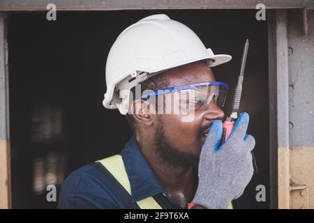 L'ingegnere maschile africano controlla un con la radio che parla comunicazione o walkie talkie Foto Stock