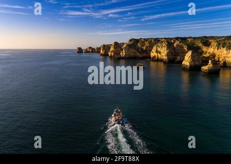 Vista aerea di una piccola barca da pesca che naviga lungo la panoramica Ponta da Piedade, vicino alla città di Lagos, in Algarve, Portogallo. Foto Stock