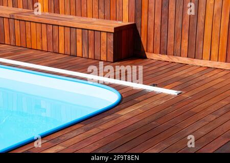 Terrazza in legno intorno alla piscina. Primo piano sul design delle terrazze a bordo piscina, struttura in legno orizzontale e verticale Foto Stock