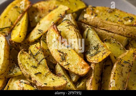 Fette di patate biologiche al rosmarino fatte in casa con sale e pepe Foto Stock