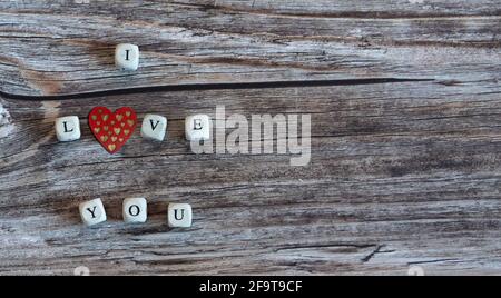 Dadi che formano la parola 'ti amo' su uno sfondo di legno. Spazio di copia. Foto Stock