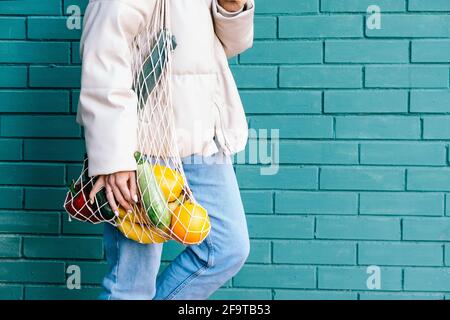 Concetto di zero sprechi. Primo piano donna che tiene riutilizzabile borsa della spesa in rete con frutta e verdura. Primo piano su eco-friendly mesh shopper. Foto Stock