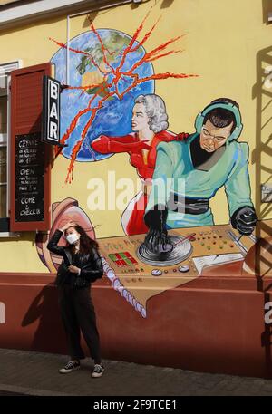 Cracovia. Cracovia. Polonia. Un murale raffigurante DJ con assistente femminile che combatte il virus attackin Terra. Una parete anteriore della barra. Posa turistica femminile. Foto Stock