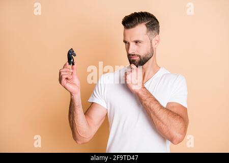 Foto di giovane bel ragazzo serio sguardo fiducioso sugli scacchi figura cavallo pensieroso isolato su sfondo di colore beige Foto Stock