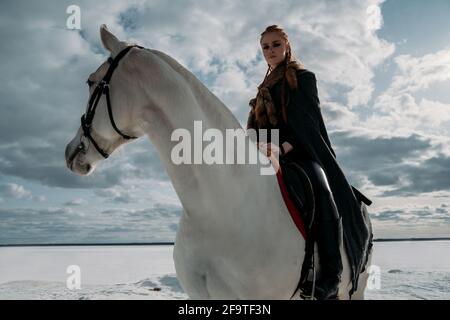 Giovane donna vichinga con capelli rossi cavalcano un cavallo. Luce straordinaria. Gioco di ruolo Foto Stock