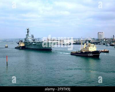 AJAXNETPHOTO. 1984. PORTSMOUTH, ENLAND. - SCRAPYARD BOUND - LA PORTAEREI HMS BALUARDO CHE È STATO TRAINATO DALLA BASE NAVALE AL DEPOSITO DI ROTTAMI NEL 1984. FOTO:JONATHAN EASTLAND/AJAX. REF:842 Foto Stock