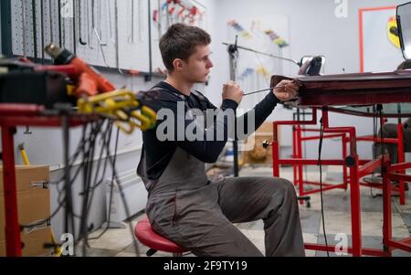 Rimozione delle ammaccature processo di lavoro di un giovane datore di lavoro professionale di riparazione auto Foto Stock