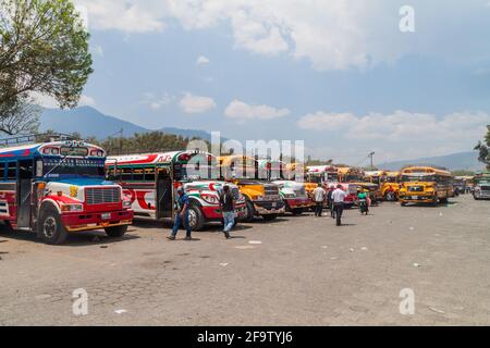 ANTIGUA, GUATEMALA - 28 MARZO 2016: I colorati autobus di pollo, ex autobus scolastici statunitensi, sono allineati al terminal principale degli autobus nella città di Antigua Guatemala. Foto Stock