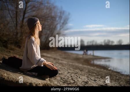 Pratica della meditazione e dell'interazione con la natura. Ragazza vicino al fiume Foto Stock