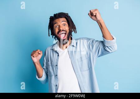 Ritratto di attraente ragazzo allegro che indossa una camicia di jeans che celebra avere divertimento isolato su sfondo di colore blu brillante Foto Stock