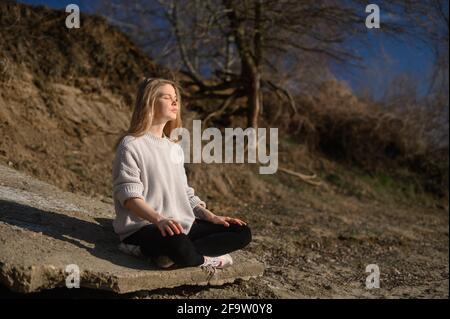 Pratica della meditazione e dell'interazione con la natura. Ragazza vicino al fiume Foto Stock