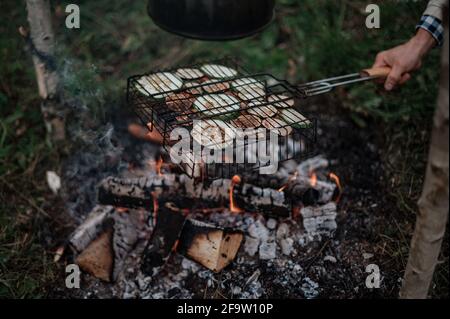 Accoppia in un plaid a scacchi arrostendo marshmallows sul fuoco vicino alla casa del rimorchio. Foto Stock