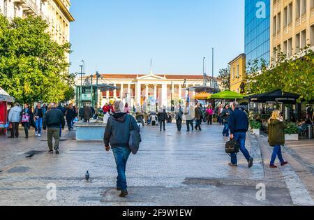 ATENE, GRECIA, 10 DICEMBRE 2015: La gente sta camminando attraverso l'ampia strada pedonale con la costruzione dell'università di atene dietro di loro Foto Stock