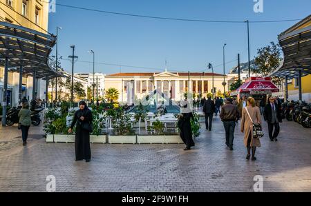 ATENE, GRECIA, 10 DICEMBRE 2015: La gente sta camminando attraverso l'ampia strada pedonale con la costruzione dell'università di atene dietro di loro Foto Stock